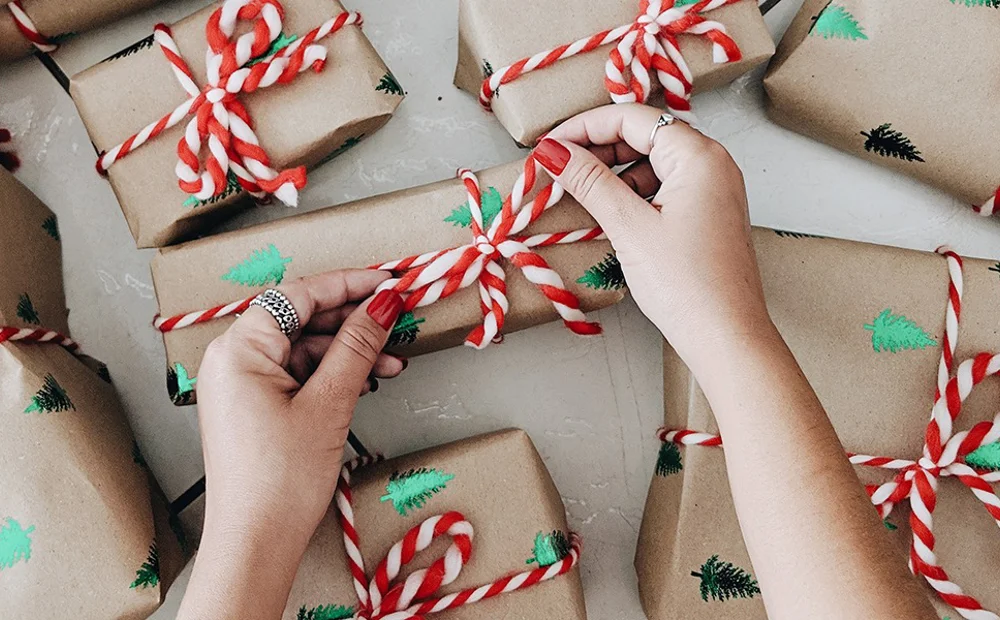 person tying striped ribbon on gifts person tying striped ribbon on gifts