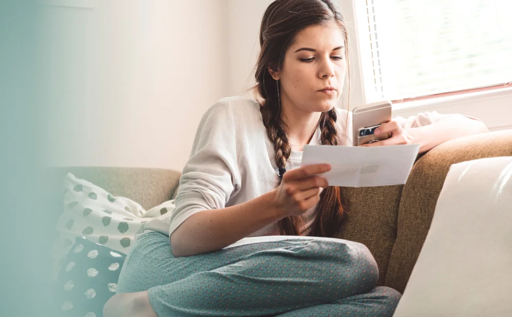 person on the sofa with phone and paper in hand person on the sofa with phone and paper in hand